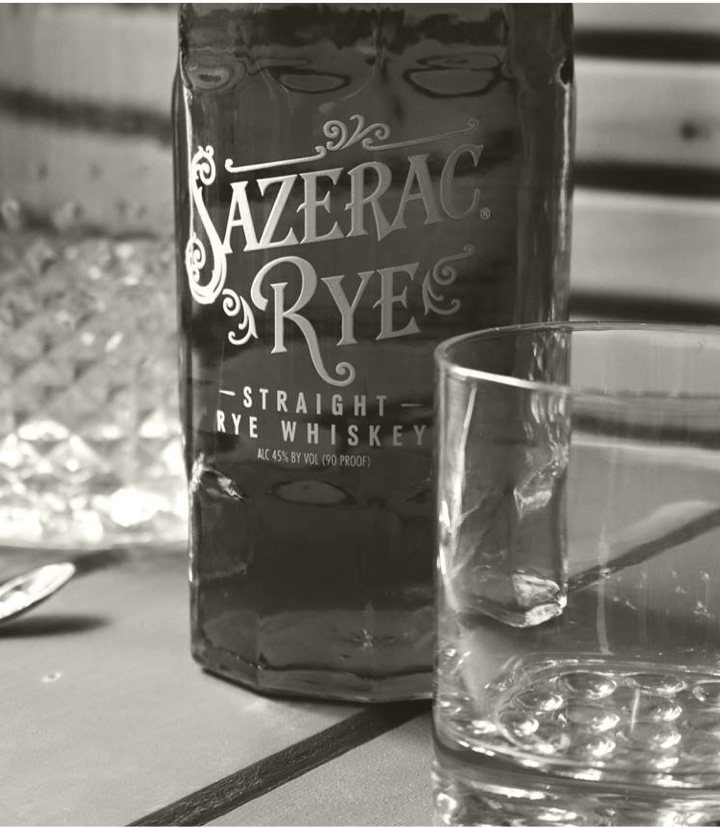 Black and white closeup of Sazerac Rye bottle and empty rocks glass