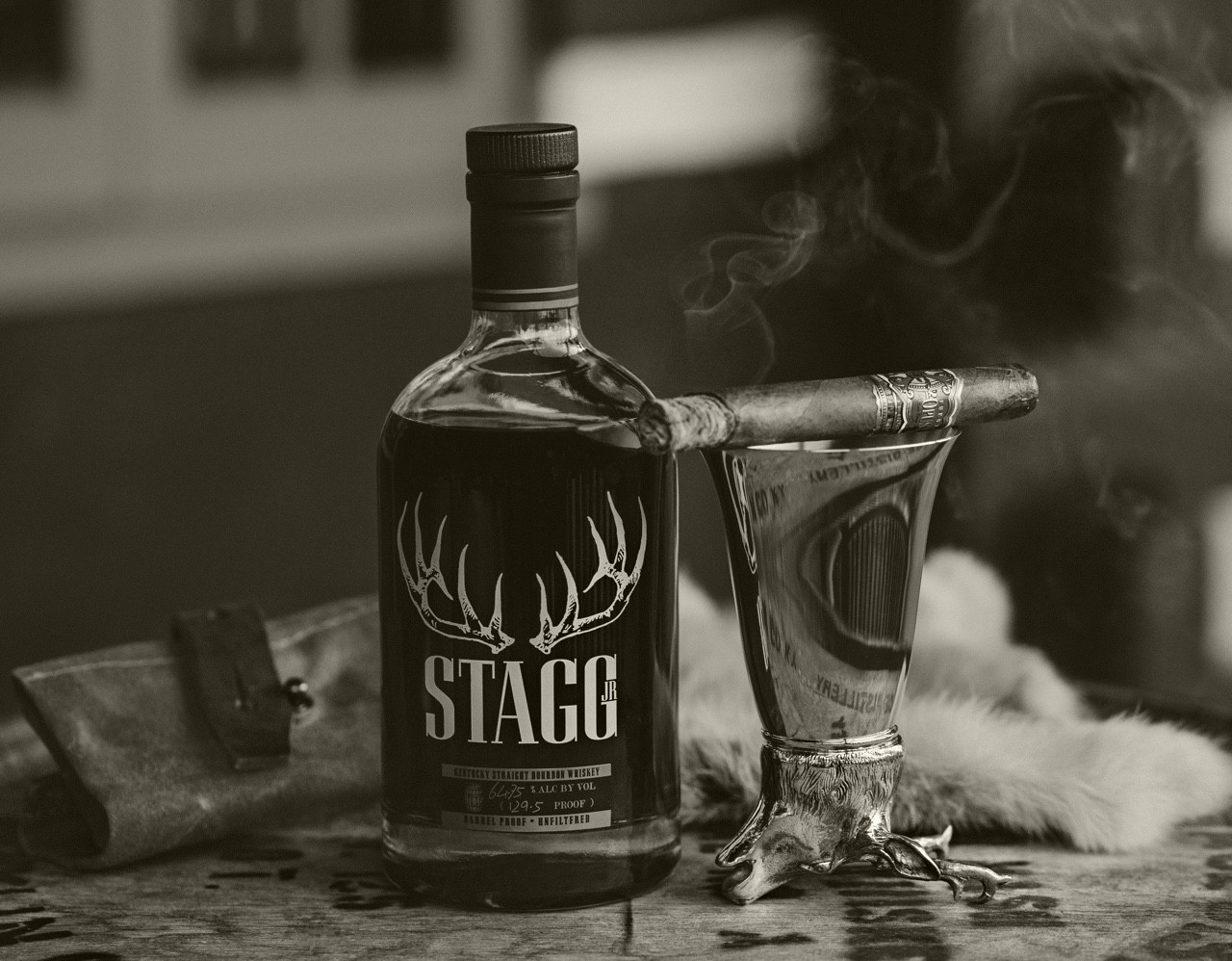 A cigar being smoked with a glass of Stagg Bourbon