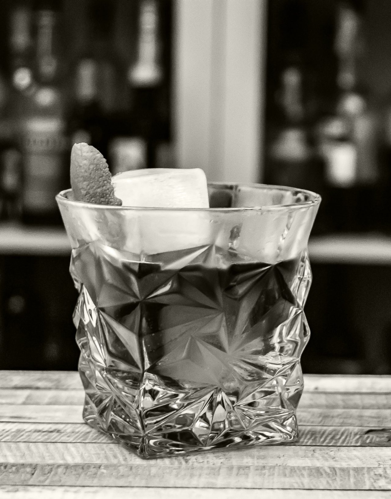 Black and white closeup of an Old Fashioned in a fancy glass
