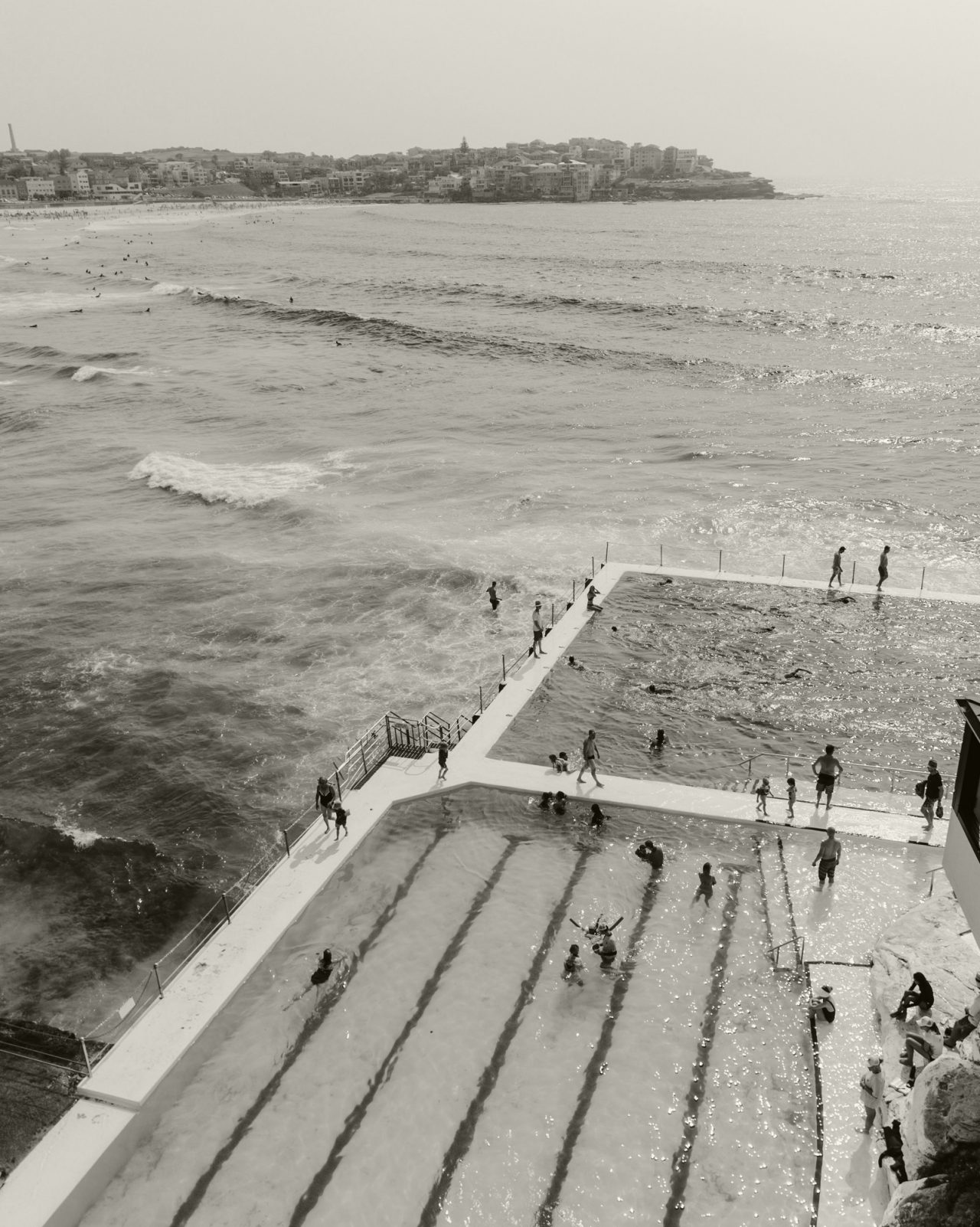 Black and white image of people swimming at a public beach in Sydney