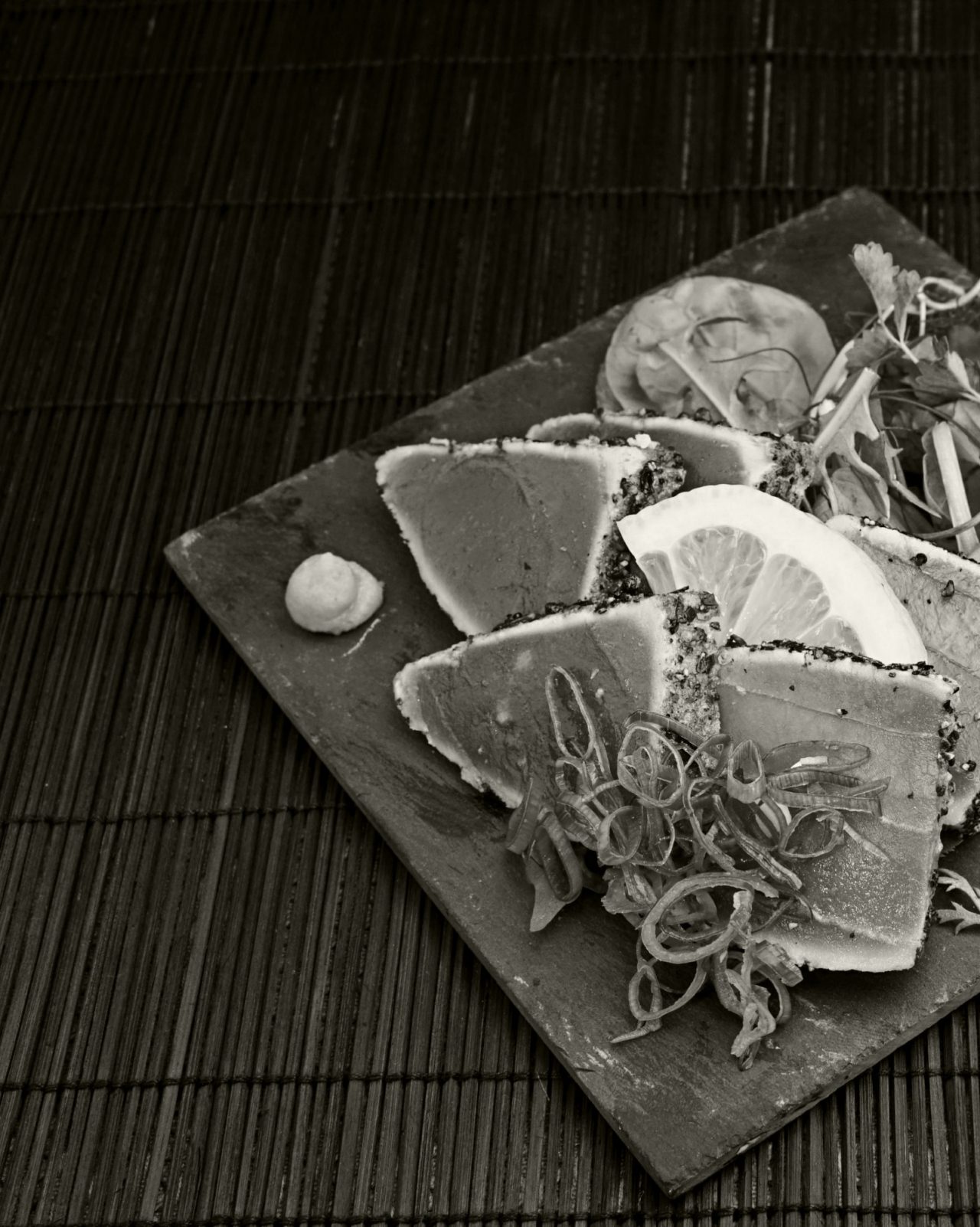 Black and white shot of seared crusted ahi tuna on platter on table