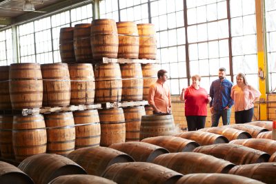 Two men and two women standing in the middle of barrels in a warehouse