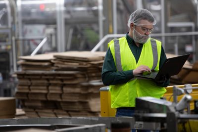Male Glenmore Distillery Worker on Laptop with lime green vest