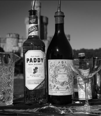Black and white lineup of the ingredients for the Paddy Cocktail with castle in background