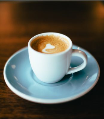 Closeup of a coffee in blue coffee mug and matching saucer on table