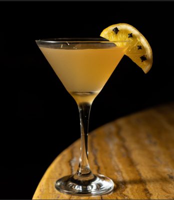Closeup of yellow martini on wood table with black background