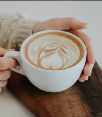 Female hands holding coffee mug with froth art