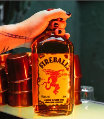Download Tattooed hard holding Fireball bottle on bartop