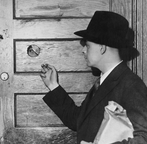 Man peeking through secret hole of bar during Prohibition
