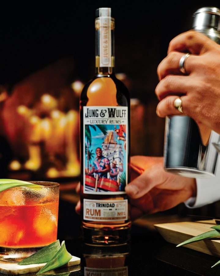 Bartender shaking cocktail shaker with cocktail in forefront