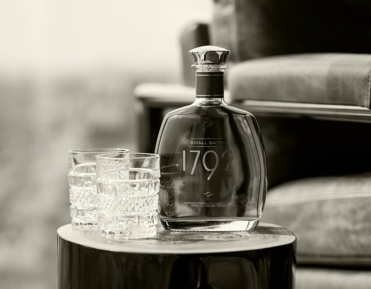 A black and white overlay of empty whiskey glasses with a 1 liter bottle of Small Batch 1792 Bourbon Whiskey