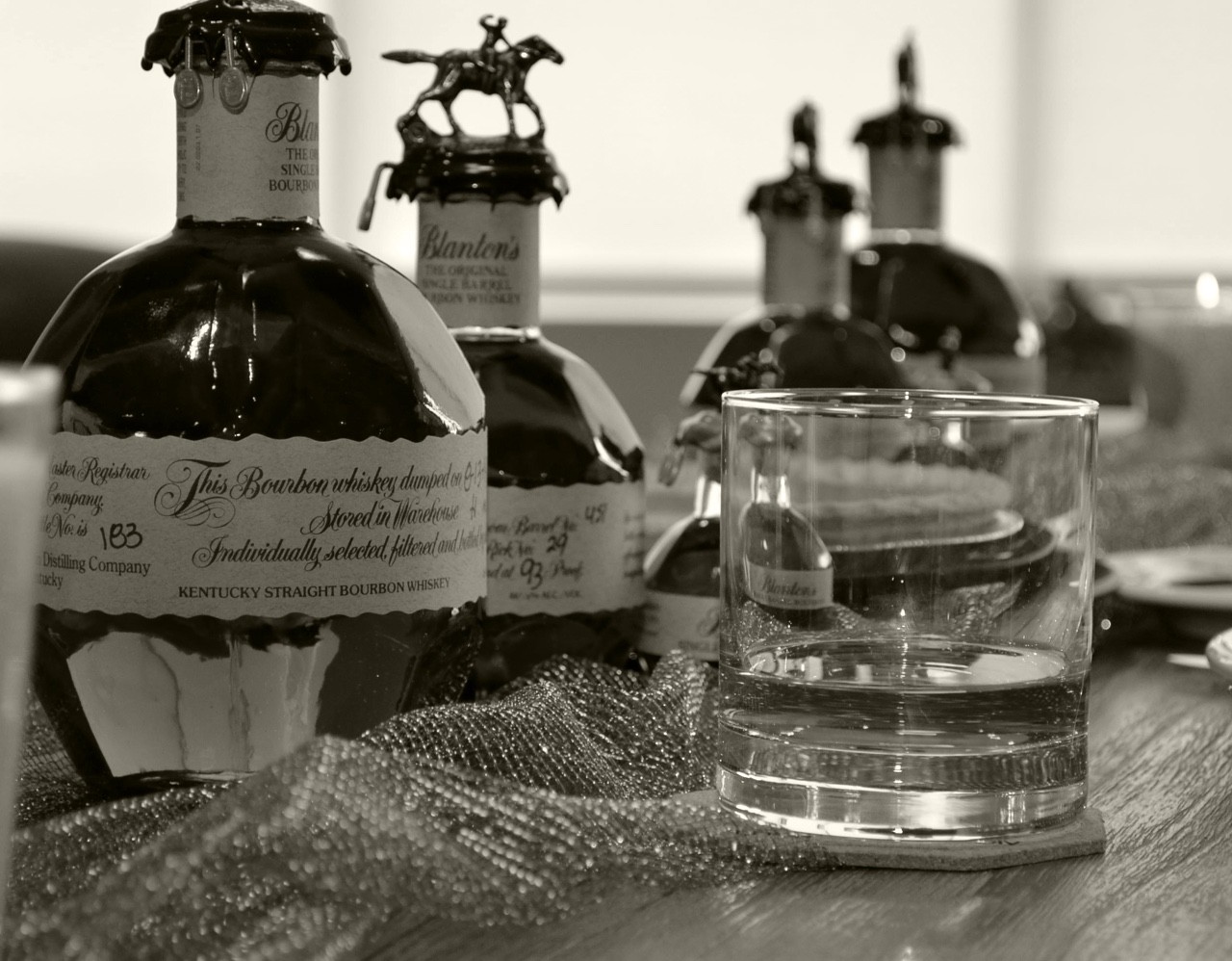 A glass filled with Blanton's Original Single Barrel Bourbon Whiskey with other varieties