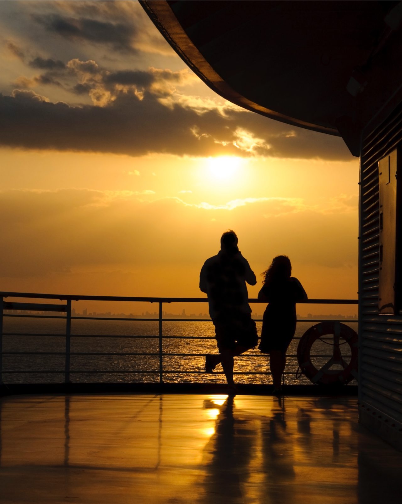 Two people standing on boat watching sunset