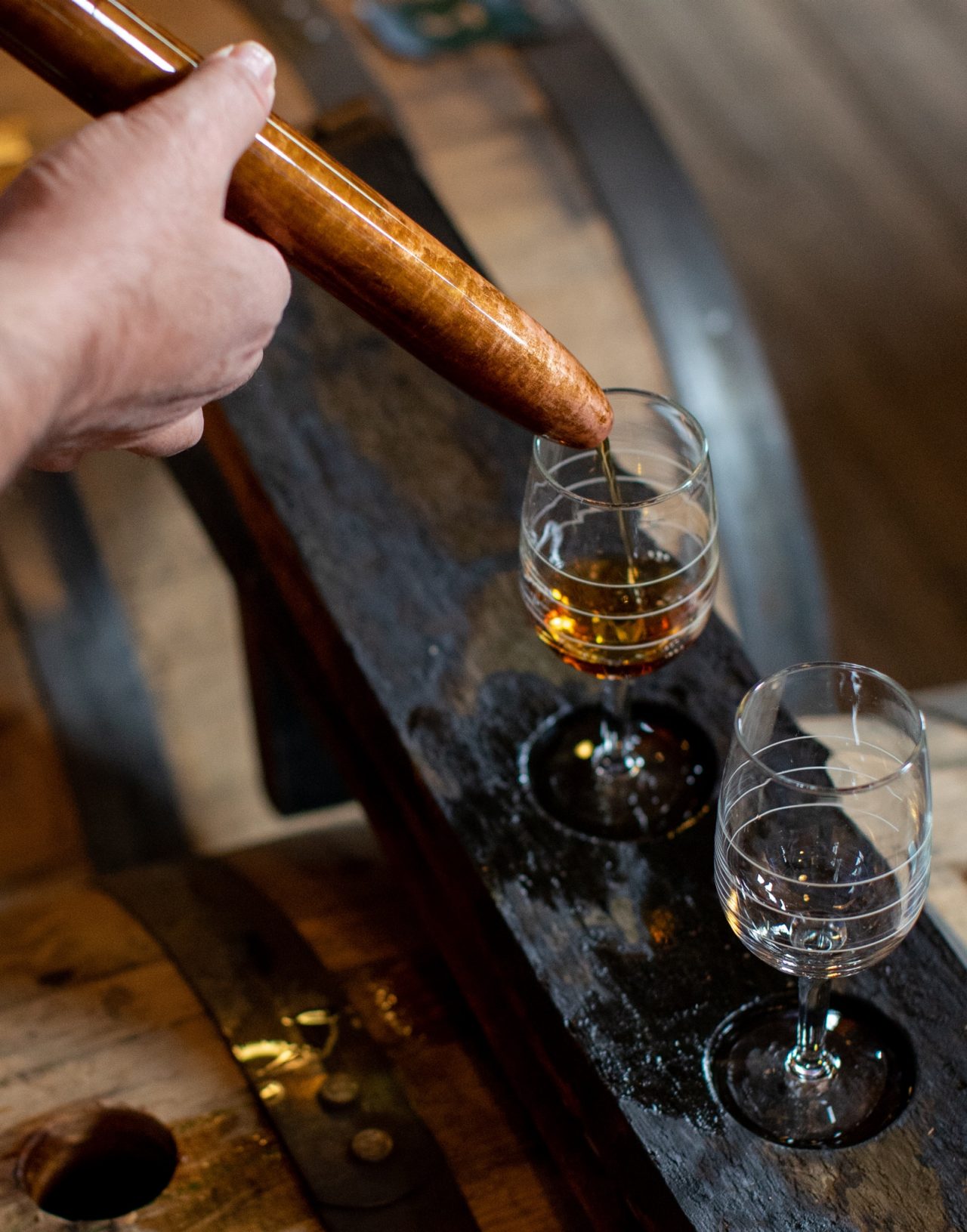 Closeup of hand pouring whiskey straight from barrel into glass