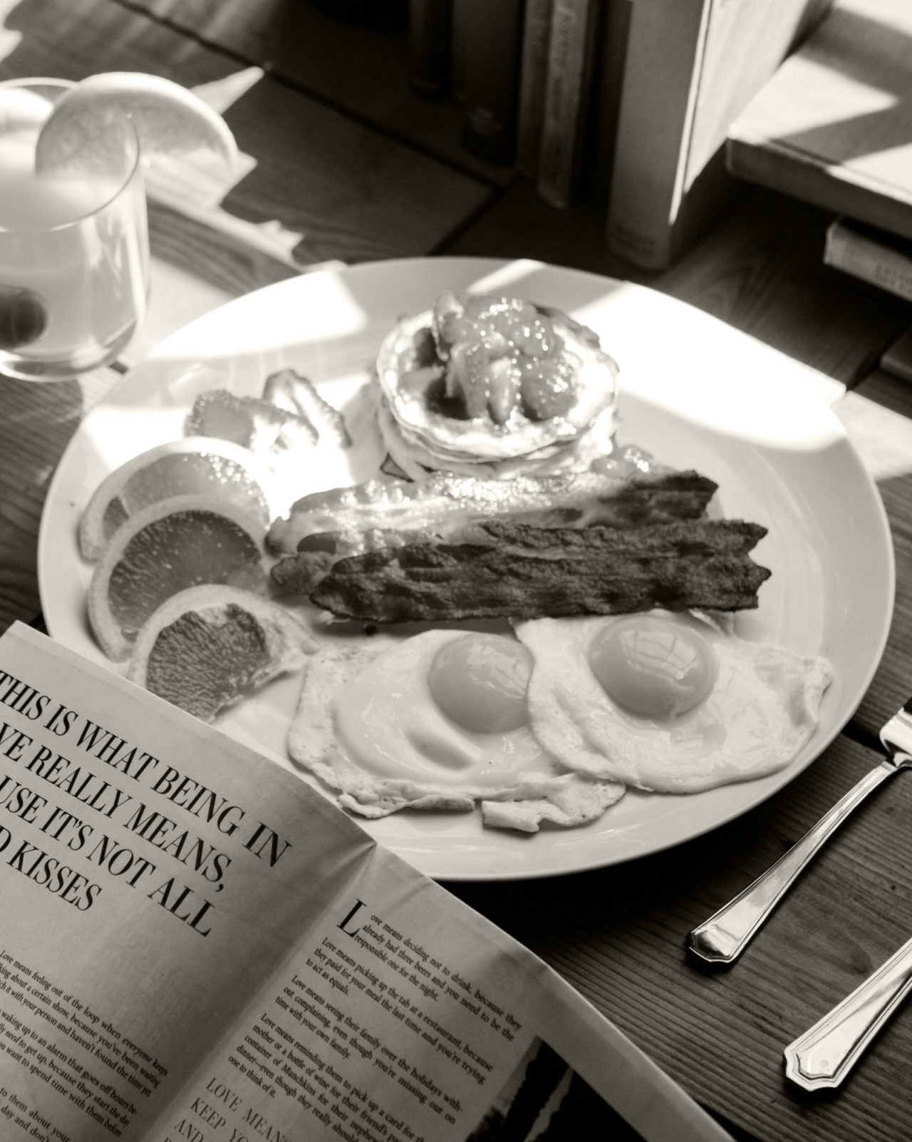 Black and white traditional English breakfast plate on table with person reading newspaper