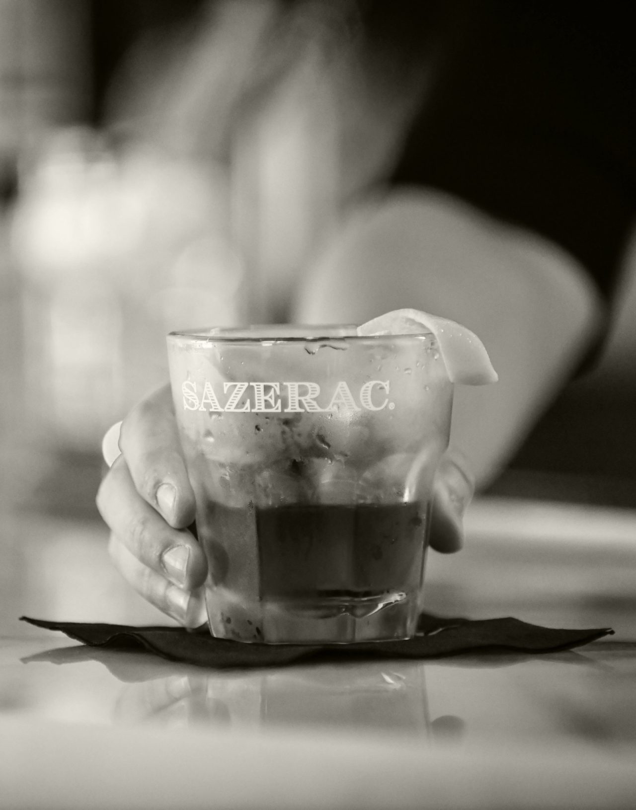 Black and white closeup of Sazerac cocktail on bartop